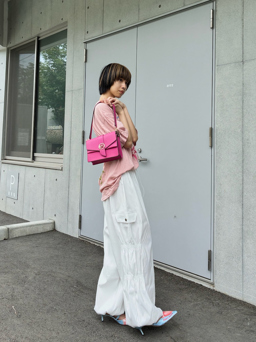 ピンク系のショルダーバッグ、ピンク系のTシャツ/カットソー、ブルー系のパンプスを着用したレディースの夏コーディネートの3枚目の写真