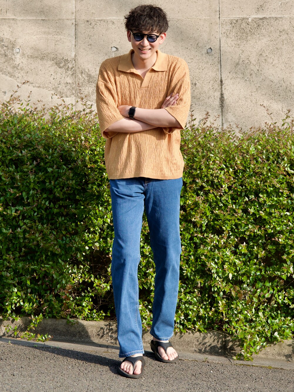 イエロー系のポロシャツ、ブラック系のサンダル、ブルー系のデニムパンツを着用したメンズの春コーディネートの4枚目の写真