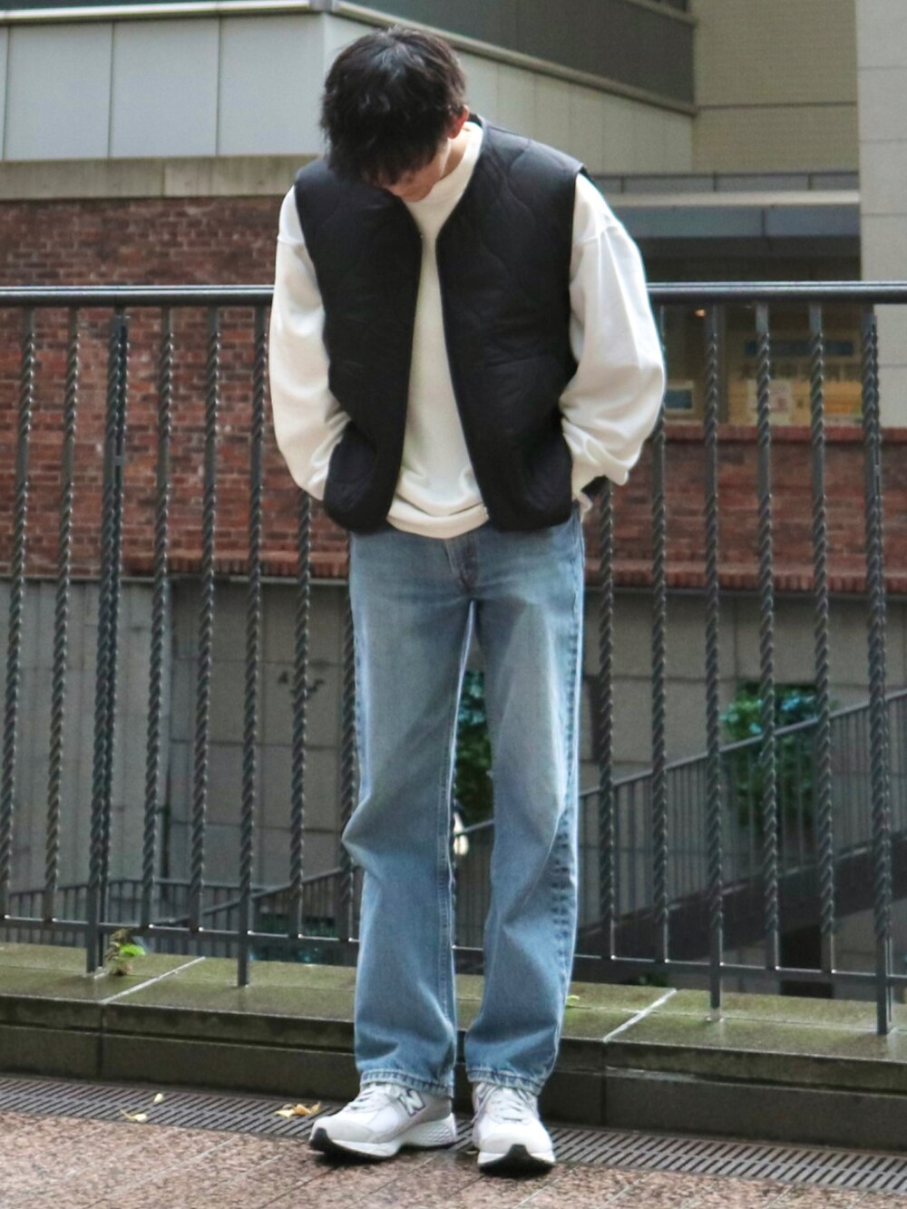 ブラック系のベスト、ホワイト系のスウェット、ブルー系のデニムパンツを着用したメンズの秋コーディネートの2枚目の写真