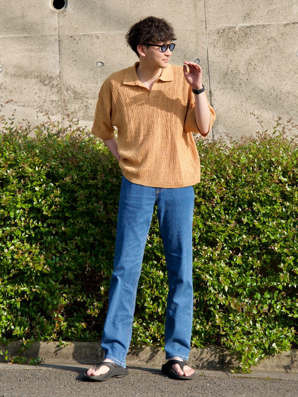 イエロー系のポロシャツ、ブラック系のサンダル、ブルー系のデニムパンツを着用したメンズの春コーディネートの2枚目の写真