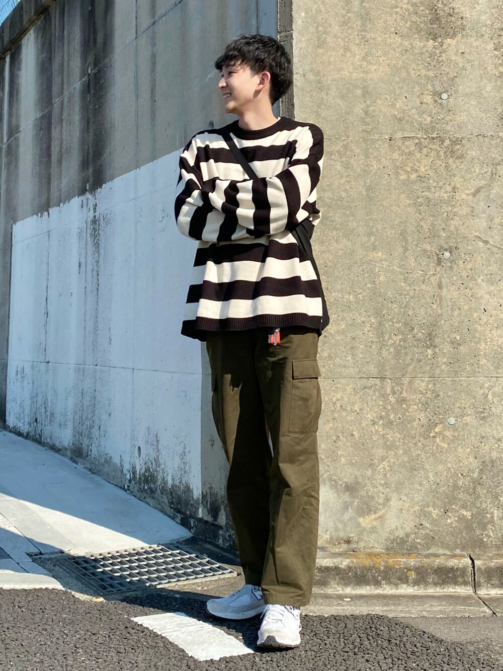 ブラック系のニット/セーター、グリーン系のカーゴパンツ、グレー系のスニーカーを着用したメンズの春コーディネートの2枚目の写真
