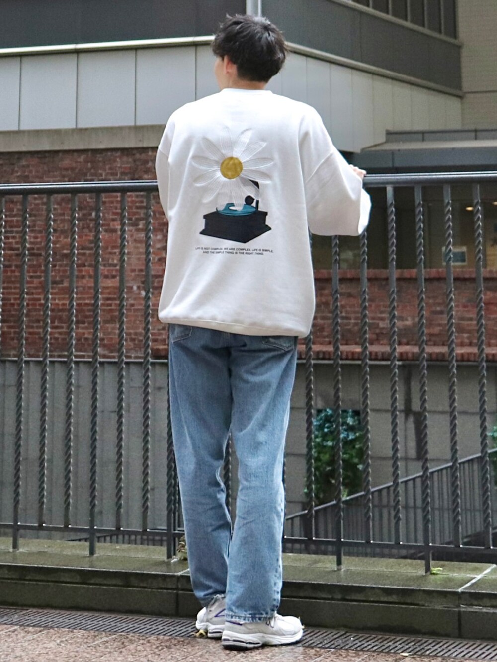 ブラック系のベスト、ホワイト系のスウェット、ブルー系のデニムパンツを着用したメンズの秋コーディネートの3枚目の写真