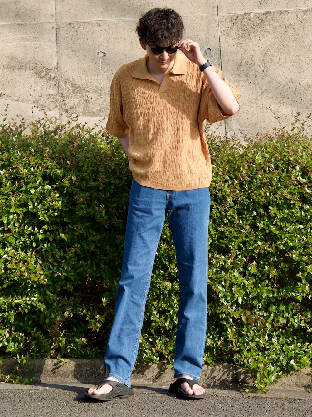 イエロー系のポロシャツ、ブラック系のサンダル、ブルー系のデニムパンツを着用したメンズの春コーディネートの3枚目の写真