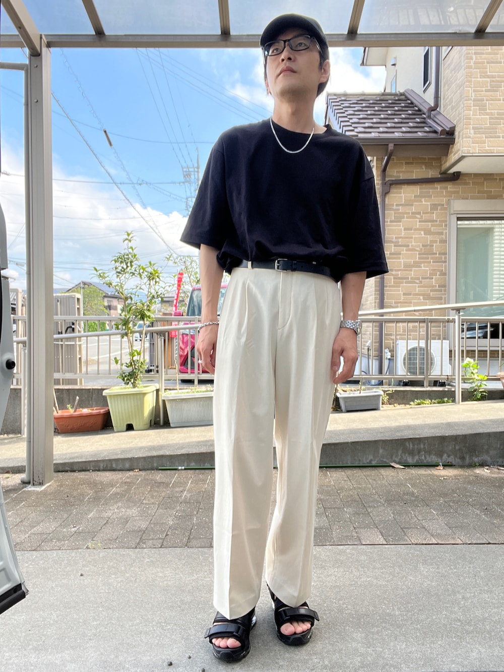 ブラック系のTシャツ/カットソー、ホワイト系のスラックス、ブラック系のサンダルを着用したメンズの夏コーディネートの2枚目の写真