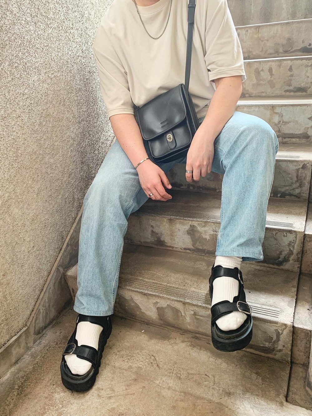 ホワイト系のタンクトップ、ブラック系のサンダル、ブルー系のデニムパンツを着用したメンズの夏コーディネートの2枚目の写真