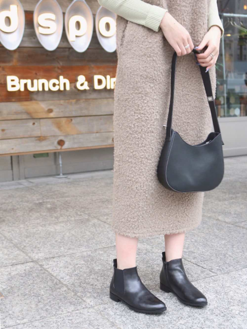 ブラウン系のワンピース、グリーン系のニット/セーター、ブラック系のブーツを着用したレディースの冬コーディネートの2枚目の写真