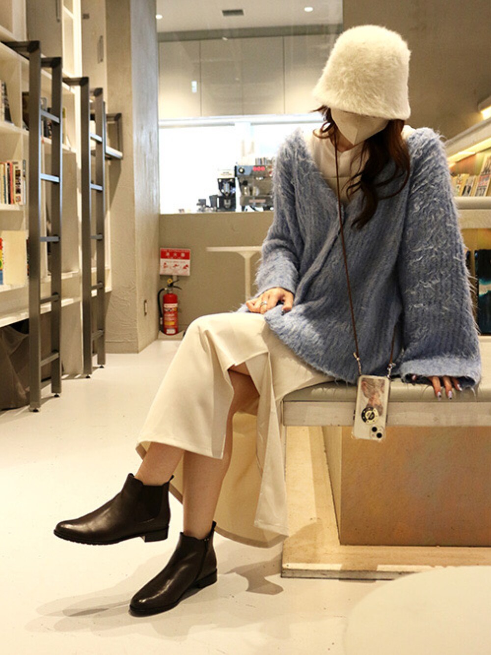 ブルー系のカーディガン/ボレロ、ブラウン系のブーツを着用したレディースの秋コーディネートの2枚目の写真