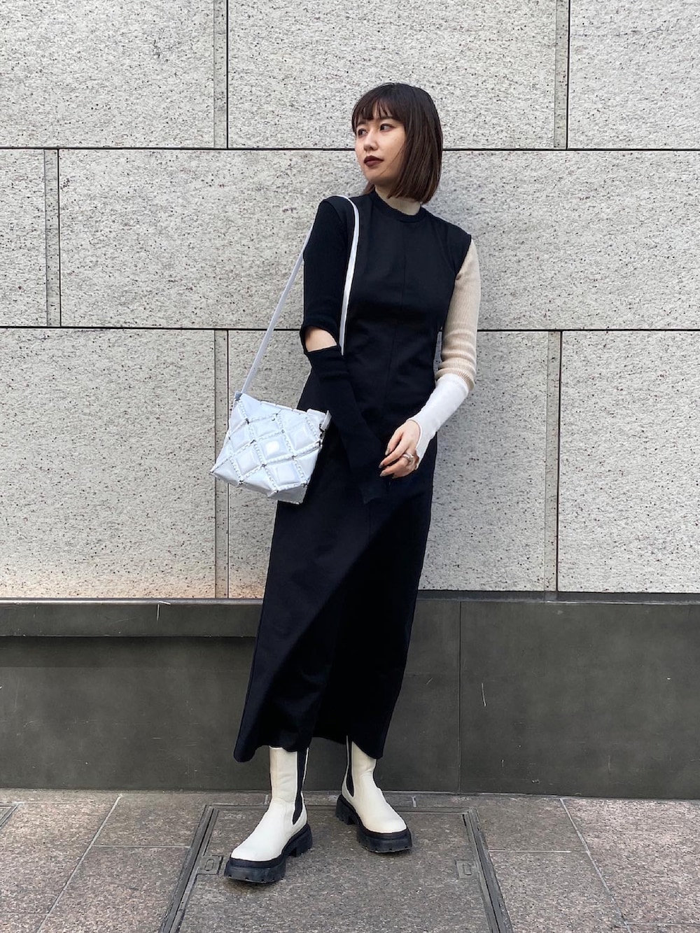 ブラック系のワンピース/ドレス、ベージュ系のニット/セーター、ホワイト系のブーツを着用したレディースの春コーディネートの2枚目の写真