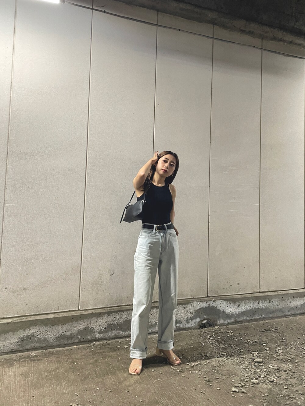 ブラック系のタンクトップ、ブラック系のハンドバッグ、ブルー系のデニムパンツを着用したレディースの夏コーディネートの2枚目の写真