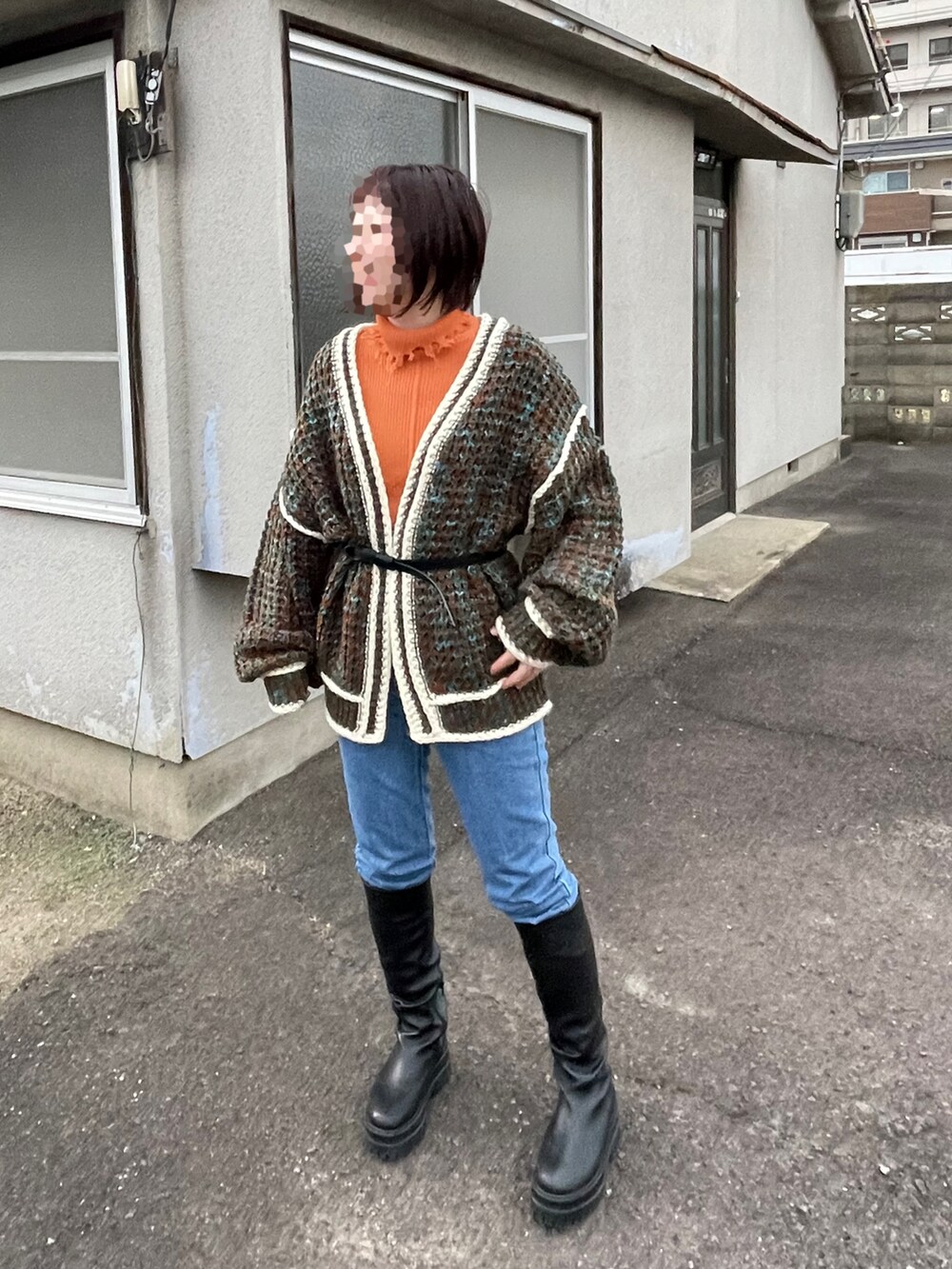 ブラウン系のカーディガン/ボレロ、ブルー系のデニムパンツ、ブラック系のブーツを着用したレディースの冬コーディネートの2枚目の写真