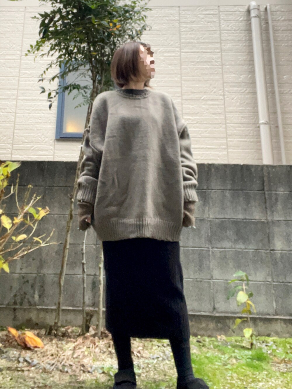 グレー系のニット/セーター、ブラック系のスカート、ブラック系のスニーカーを着用したレディースの冬コーディネートの2枚目の写真