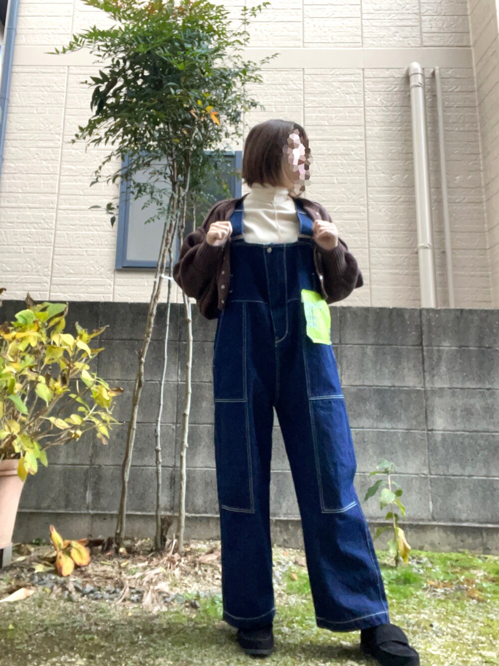 ブルー系のサロペット/オーバーオール、ホワイト系のTシャツ/カットソー、ブラウン系のワンピースを着用したレディースの冬コーディネートの3枚目の写真