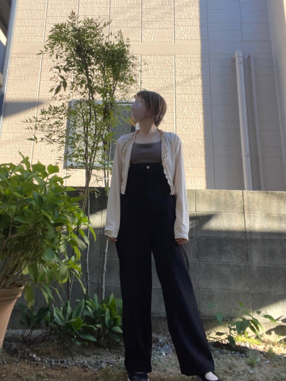 ブラック系のサロペット/オーバーオール、ホワイト系のカーディガン/ボレロ、ブラウン系のキャミソールを着用したレディースの夏コーディネートの2枚目の写真