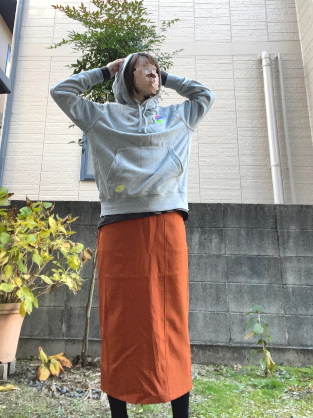 オレンジ系のスカート、グレー系のパーカーを着用したレディースの冬コーディネートの2枚目の写真