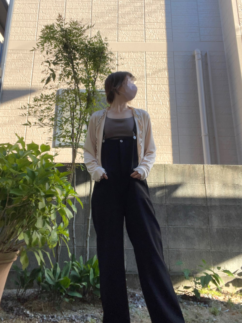 ブラック系のサロペット/オーバーオール、ホワイト系のカーディガン/ボレロ、ブラウン系のキャミソールを着用したレディースの夏コーディネートの3枚目の写真