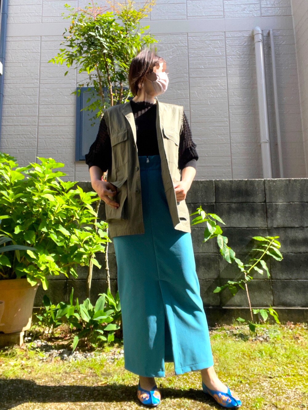 グリーン系のベスト、ブルー系のスカート、ブルー系のシューズを着用したレディースの春コーディネートの2枚目の写真
