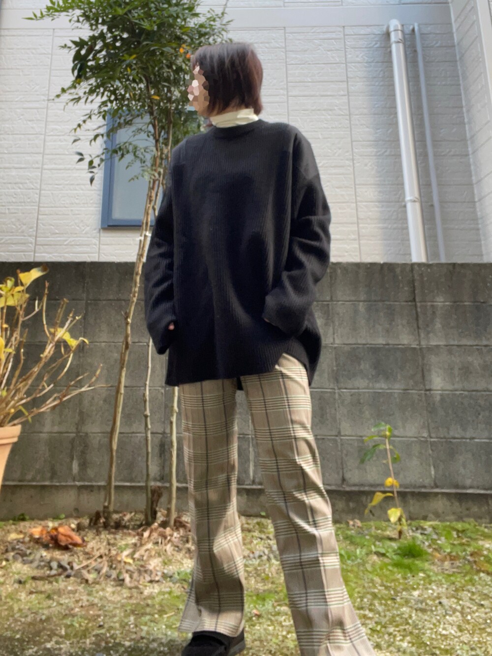 ブラック系のニット/セーター、ベージュ系のパンツ、ブラック系のスニーカーを着用したレディースの冬コーディネートの2枚目の写真