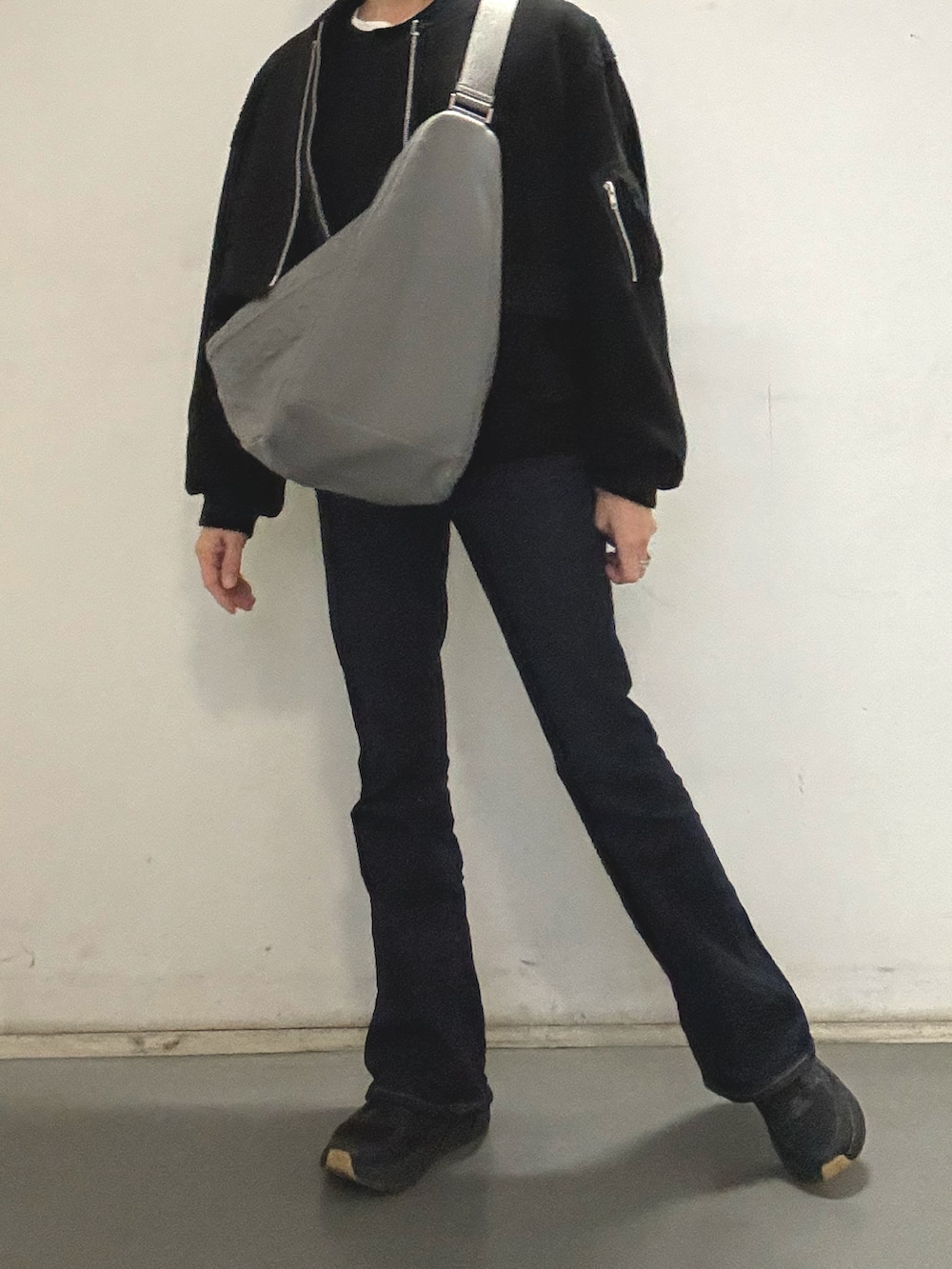 ブラック系のスニーカー、ブルー系のデニムパンツ、グレー系のショルダーバッグを着用したレディースの冬コーディネートの2枚目の写真