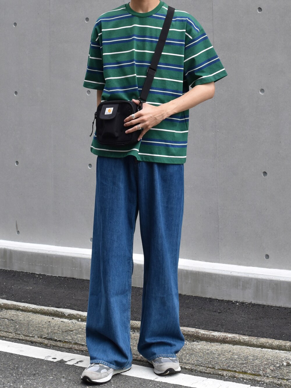 グリーン系のTシャツ/カットソー、ブルー系のデニムパンツ、グレー系のスニーカーを着用したメンズの夏コーディネートの2枚目の写真