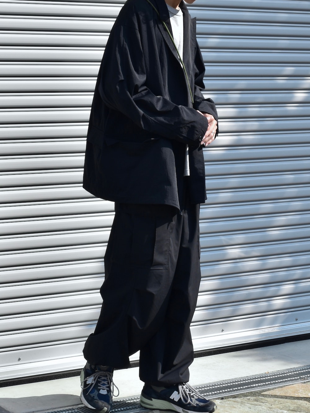 ブラック系のテーラードジャケット、ブラック系のカーゴパンツ、ブルー系のスニーカーを着用したメンズの秋コーディネートの3枚目の写真