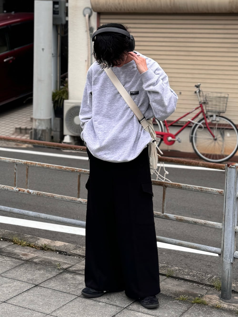 ブラック系のスラックス、ブラック系のスニーカー、ホワイト系のショルダーバッグを着用したメンズの春コーディネートの3枚目の写真