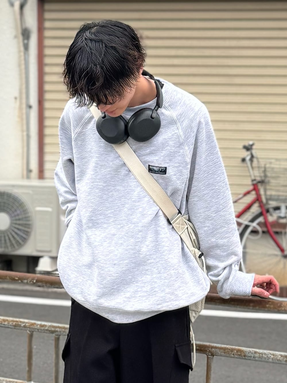 ブラック系のスラックス、ブラック系のスニーカー、ホワイト系のショルダーバッグを着用したメンズの春コーディネートの4枚目の写真