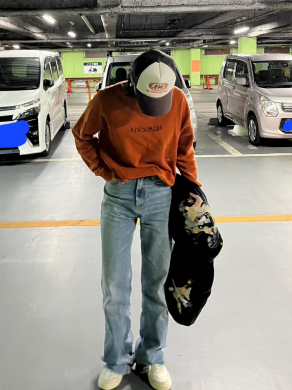 オレンジ系のスウェット、ブルー系のデニムパンツ、ホワイト系のスニーカーを着用したレディースの春コーディネートの2枚目の写真