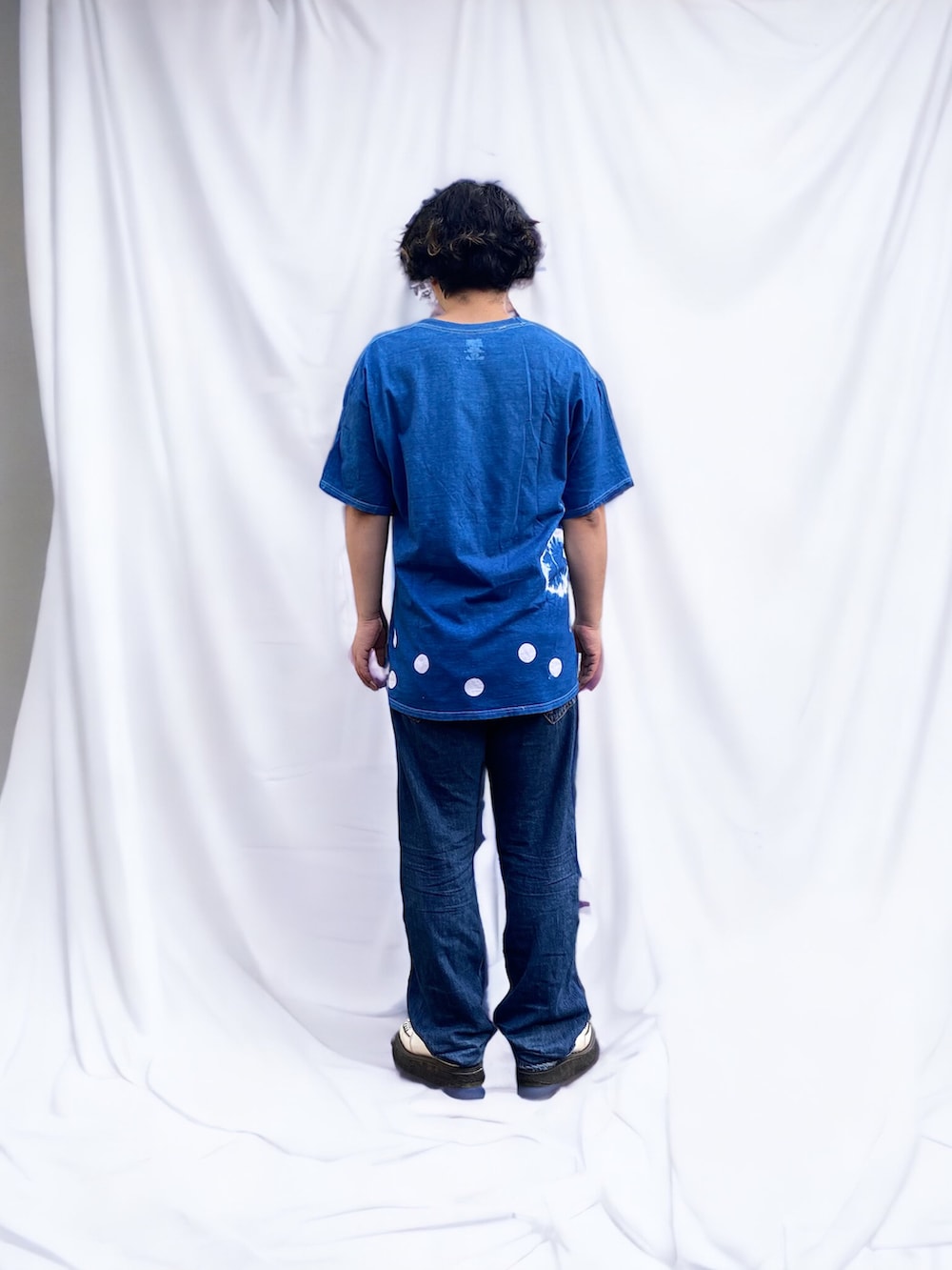 ブルー系のデニムパンツ、ホワイト系のドレスシューズ、ブルー系のTシャツ/カットソーを着用したメンズの春コーディネートの2枚目の写真