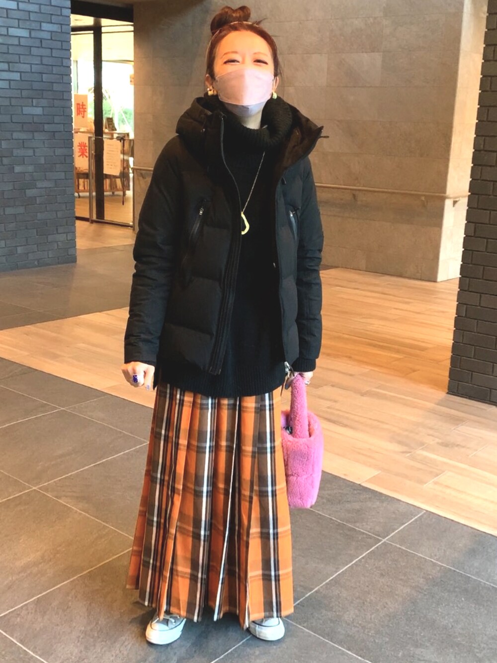 ブラック系のダウンジャケット/コート、オレンジ系のスカート、ブラック系のミリタリージャケットを着用したレディースの冬コーディネートの2枚目の写真