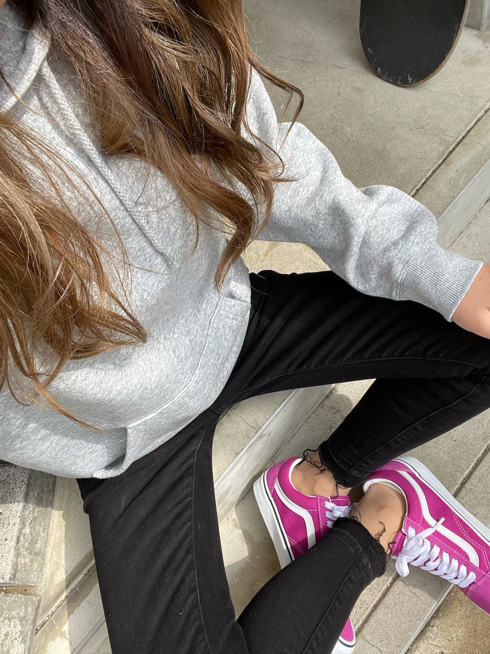 グレー系のパーカー、ブラック系のデニムパンツ、ピンク系のスニーカーを着用したレディースの春コーディネートの2枚目の写真