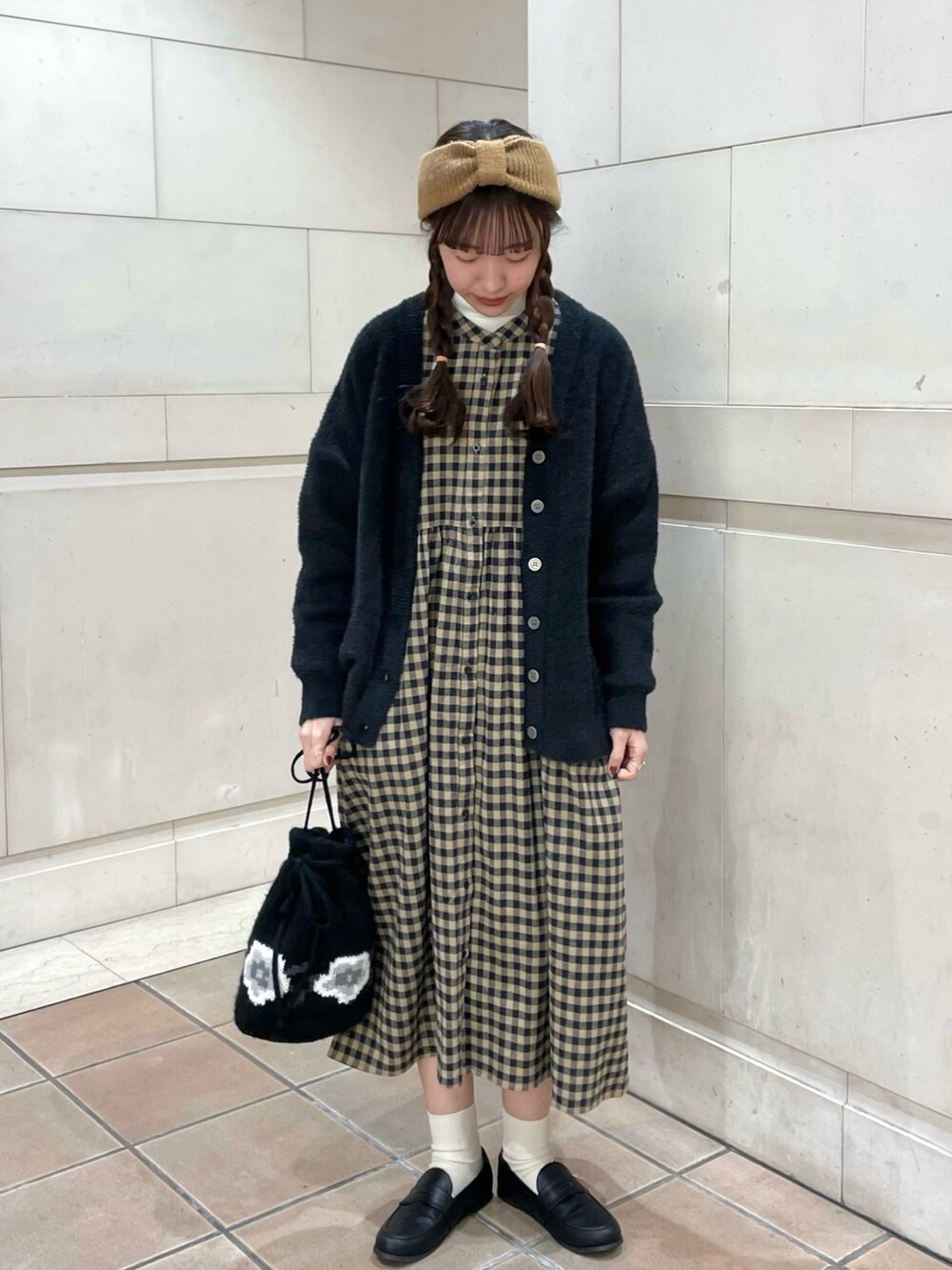 ブラック系のローファー、ブラック系のハンドバッグ、イエロー系のワンピースを着用したレディースの冬コーディネートの2枚目の写真