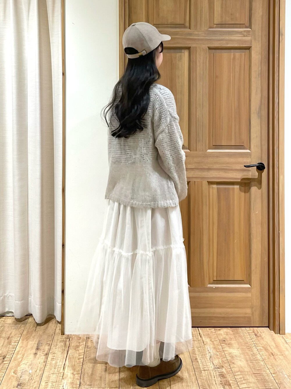 グレー系のカーディガン/ボレロ、ホワイト系のTシャツ/カットソー、ホワイト系のスカートを着用したレディースの冬コーディネートの2枚目の写真