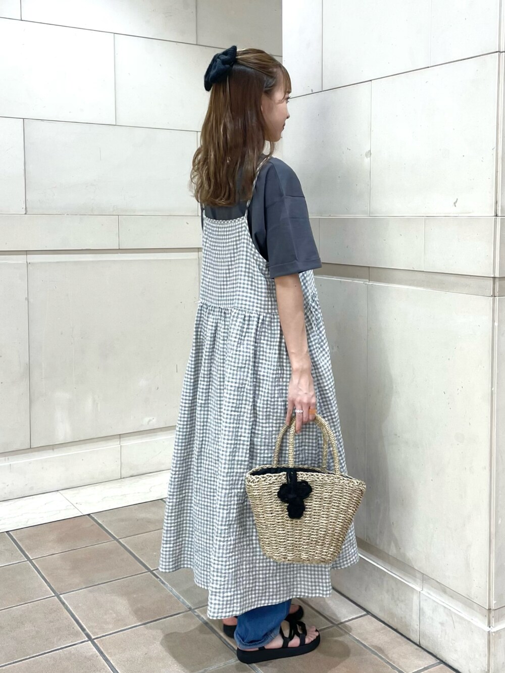 ブラック系のサンダル、ブルー系のデニムパンツ、ブラック系のかごバッグを着用したレディースの夏コーディネートの2枚目の写真