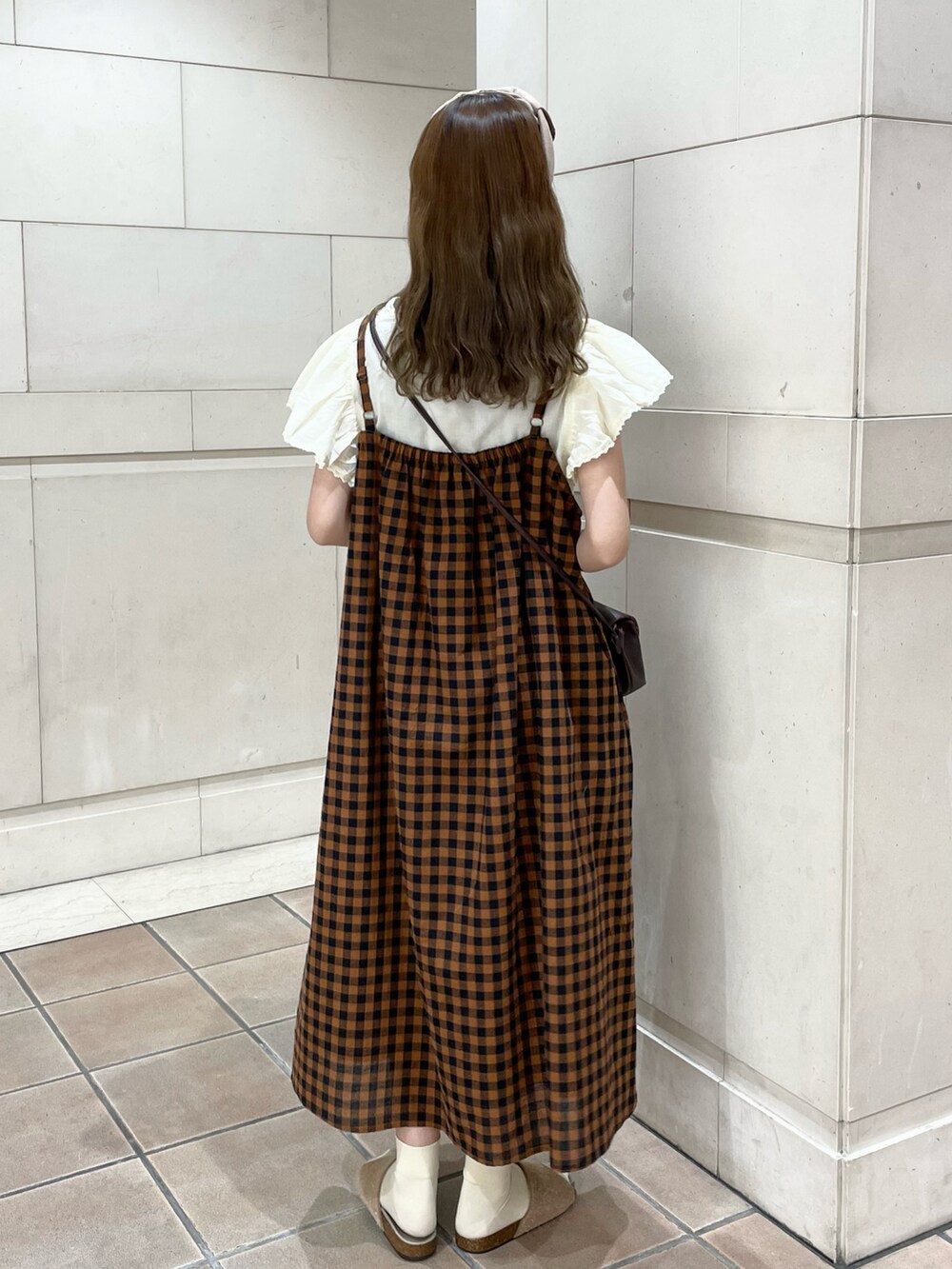 イエロー系のサンダル、ブラウン系のワンピース、ベージュ系のTシャツ/カットソーを着用したレディースの春コーディネートの2枚目の写真