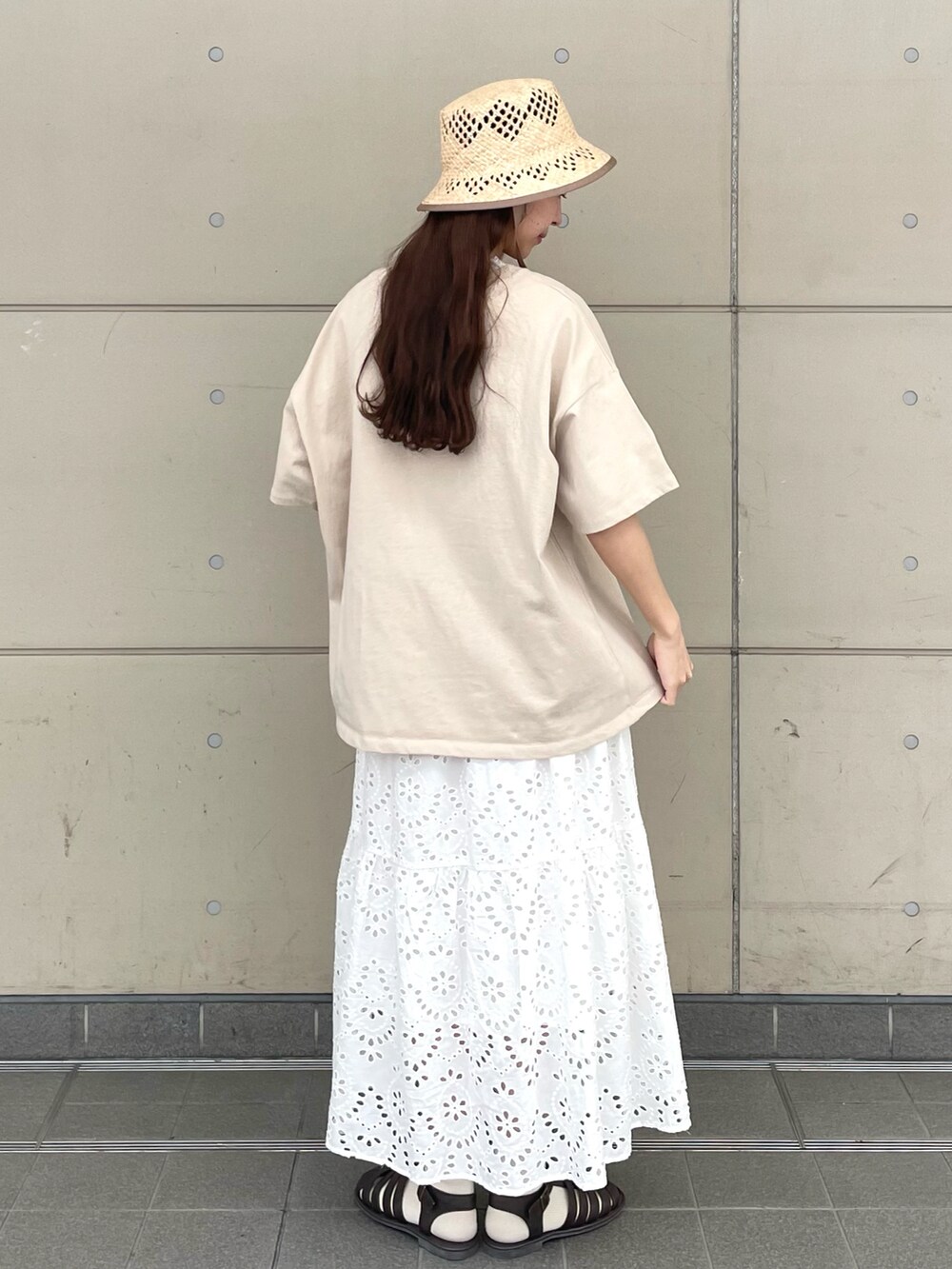 ホワイト系のスカート、ブラウン系のサンダル、ベージュ系のTシャツ/カットソーを着用したレディースの春コーディネートの2枚目の写真
