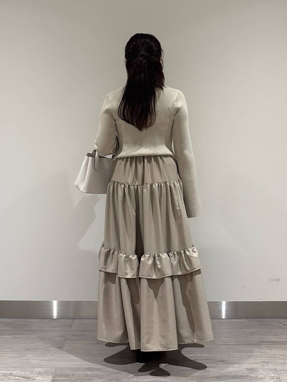 ホワイト系のショルダーバッグ、ブラック系のローファー、ベージュ系のワンピースを着用したレディースの冬コーディネートの3枚目の写真