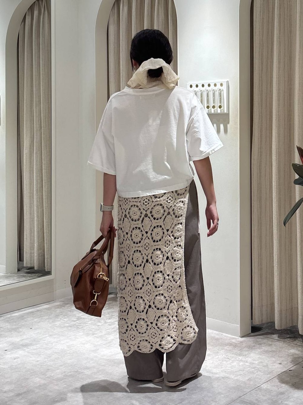 ベージュ系のスラックス、ブラウン系のボストンバッグ、ホワイト系のTシャツ/カットソーを着用したレディースの夏コーディネートの3枚目の写真