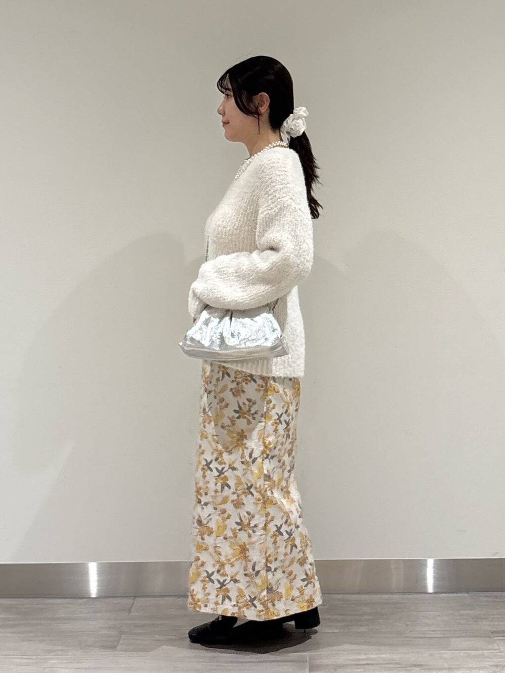 ブラック系のローファー、ホワイト系のニット/セーター、シルバー系のショルダーバッグを着用したレディースの冬コーディネートの2枚目の写真