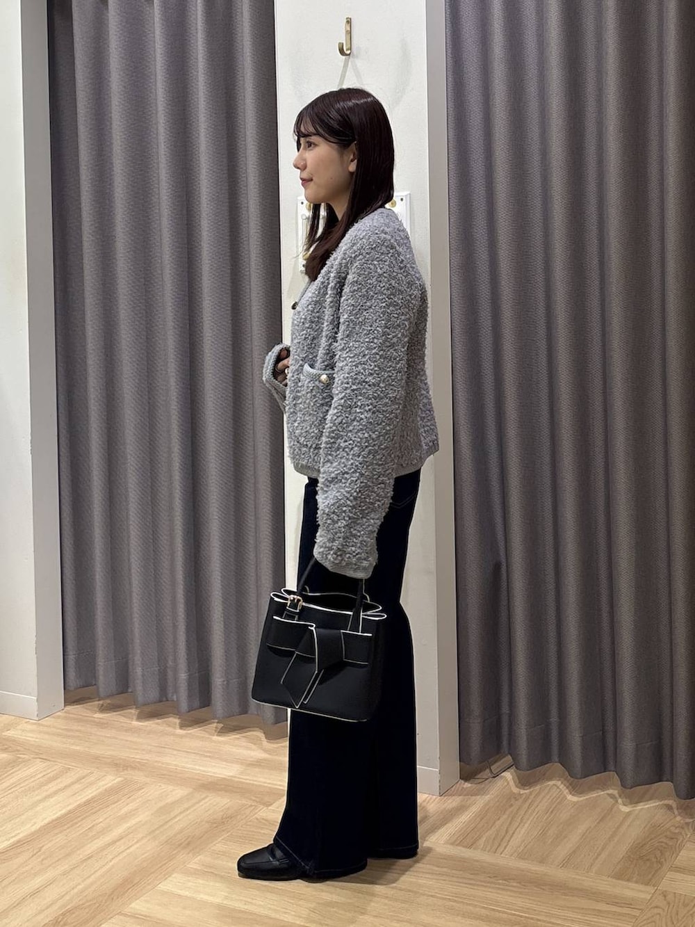 ブラック系のショルダーバッグ、グレー系のカーディガン/ボレロ、ブルー系のデニムパンツを着用したレディースの秋コーディネートの2枚目の写真