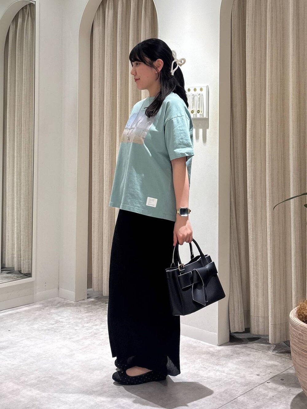 ブラック系のショルダーバッグ、ブラック系のバレエシューズ、ブラック系のスカートを着用したレディースの春コーディネートの2枚目の写真