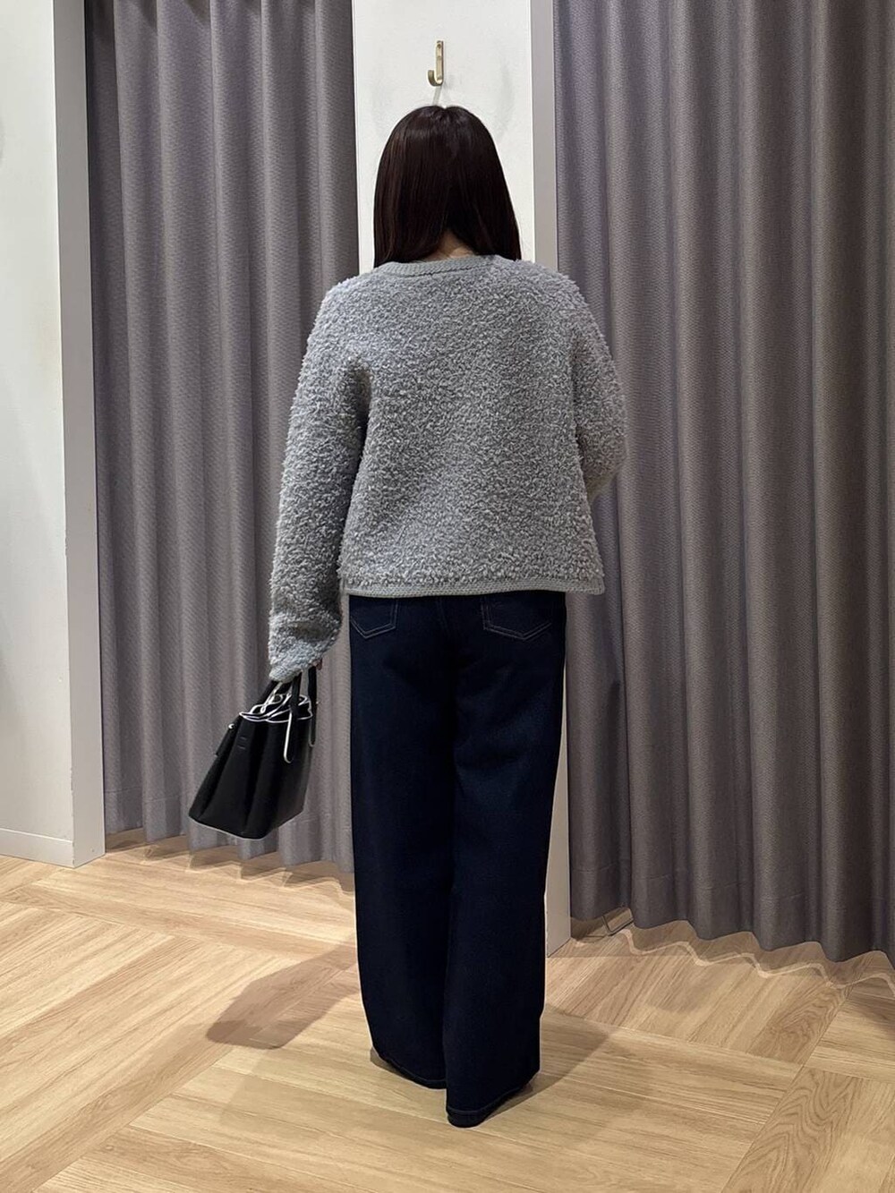 ブラック系のショルダーバッグ、グレー系のカーディガン/ボレロ、ブルー系のデニムパンツを着用したレディースの秋コーディネートの3枚目の写真