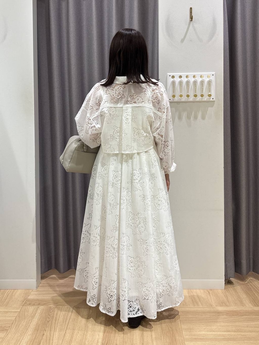 ベージュ系のハンドバッグ、ブラック系のローファー、ホワイト系のワンピースを着用したレディースの春コーディネートの3枚目の写真