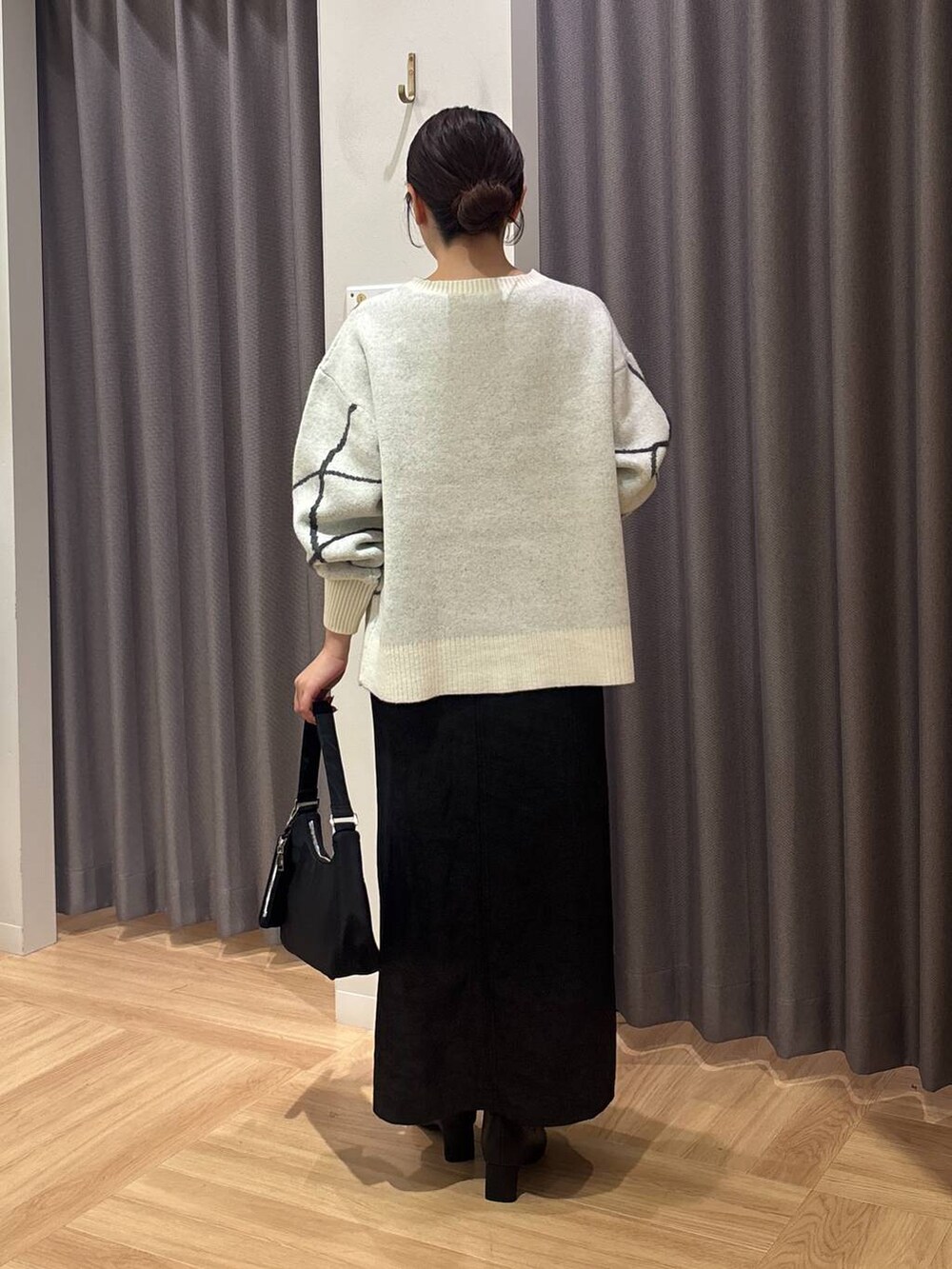 ホワイト系のニット/セーター、ブラック系のスカート、ブラック系のブーツを着用したレディースの秋コーディネートの3枚目の写真