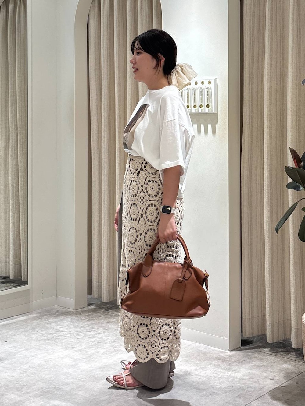 ベージュ系のスラックス、ブラウン系のボストンバッグ、ホワイト系のTシャツ/カットソーを着用したレディースの夏コーディネートの2枚目の写真
