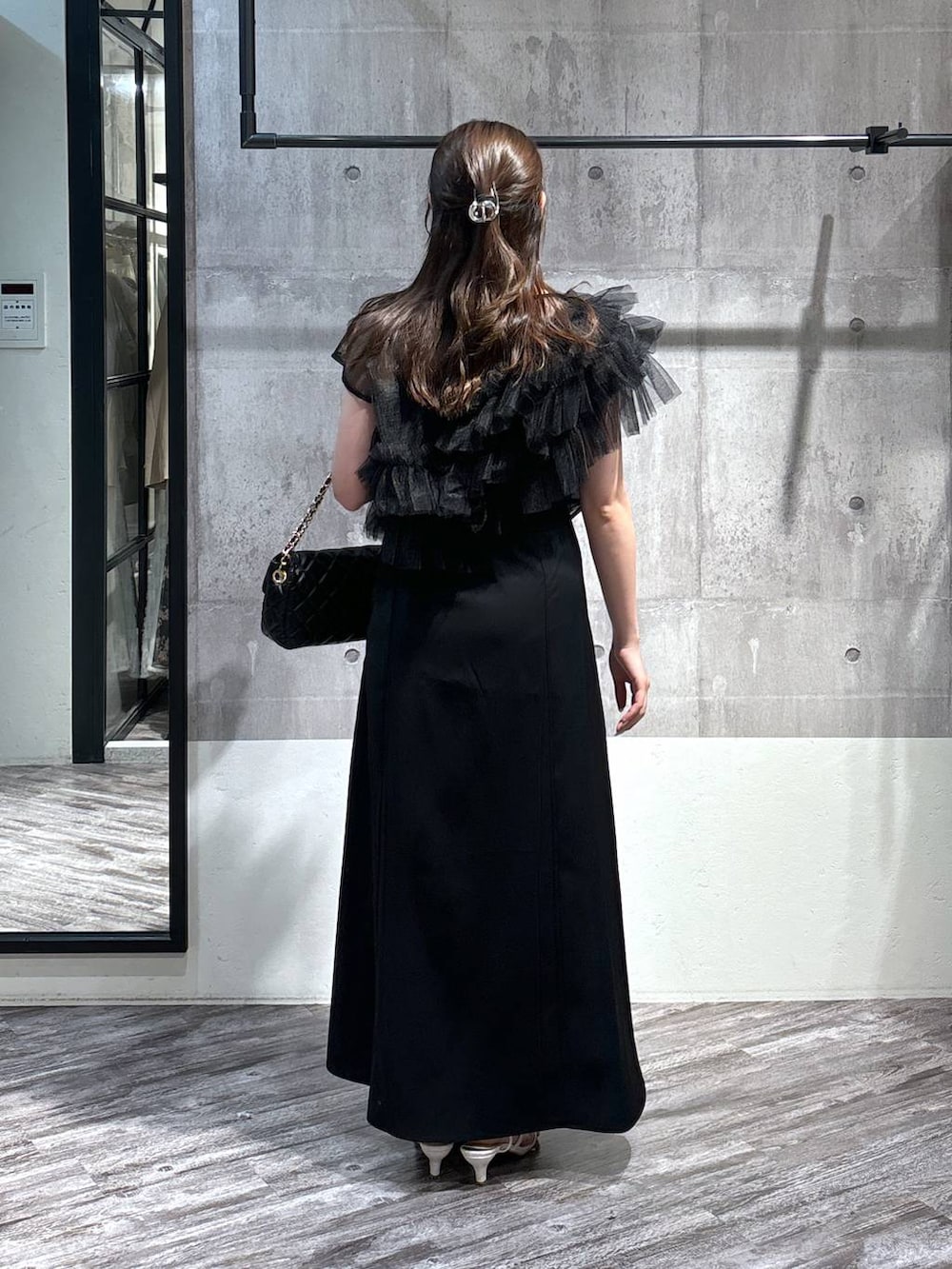 ブラック系のドレス、ブラック系のショルダーバッグ、ホワイト系のサンダルを着用したレディースの春コーディネートの2枚目の写真