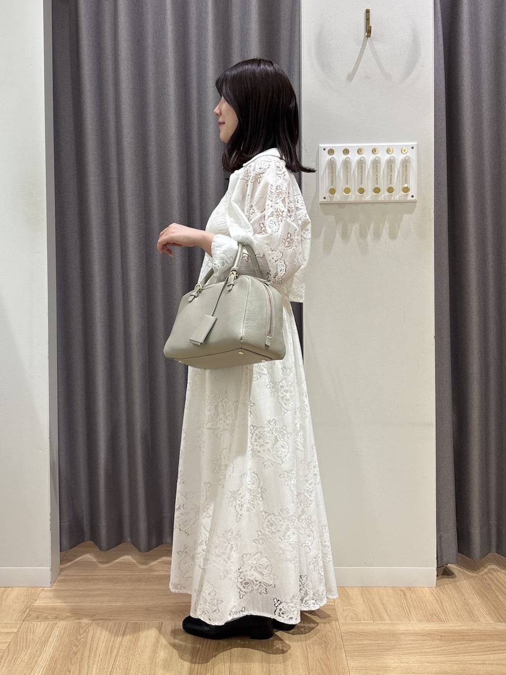 ベージュ系のハンドバッグ、ブラック系のローファー、ホワイト系のワンピースを着用したレディースの春コーディネートの2枚目の写真