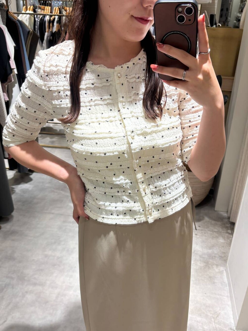 ブラック系のパンプス、ホワイト系のカーディガン/ボレロ、ベージュ系のスカートを着用したレディースの夏コーディネートの2枚目の写真