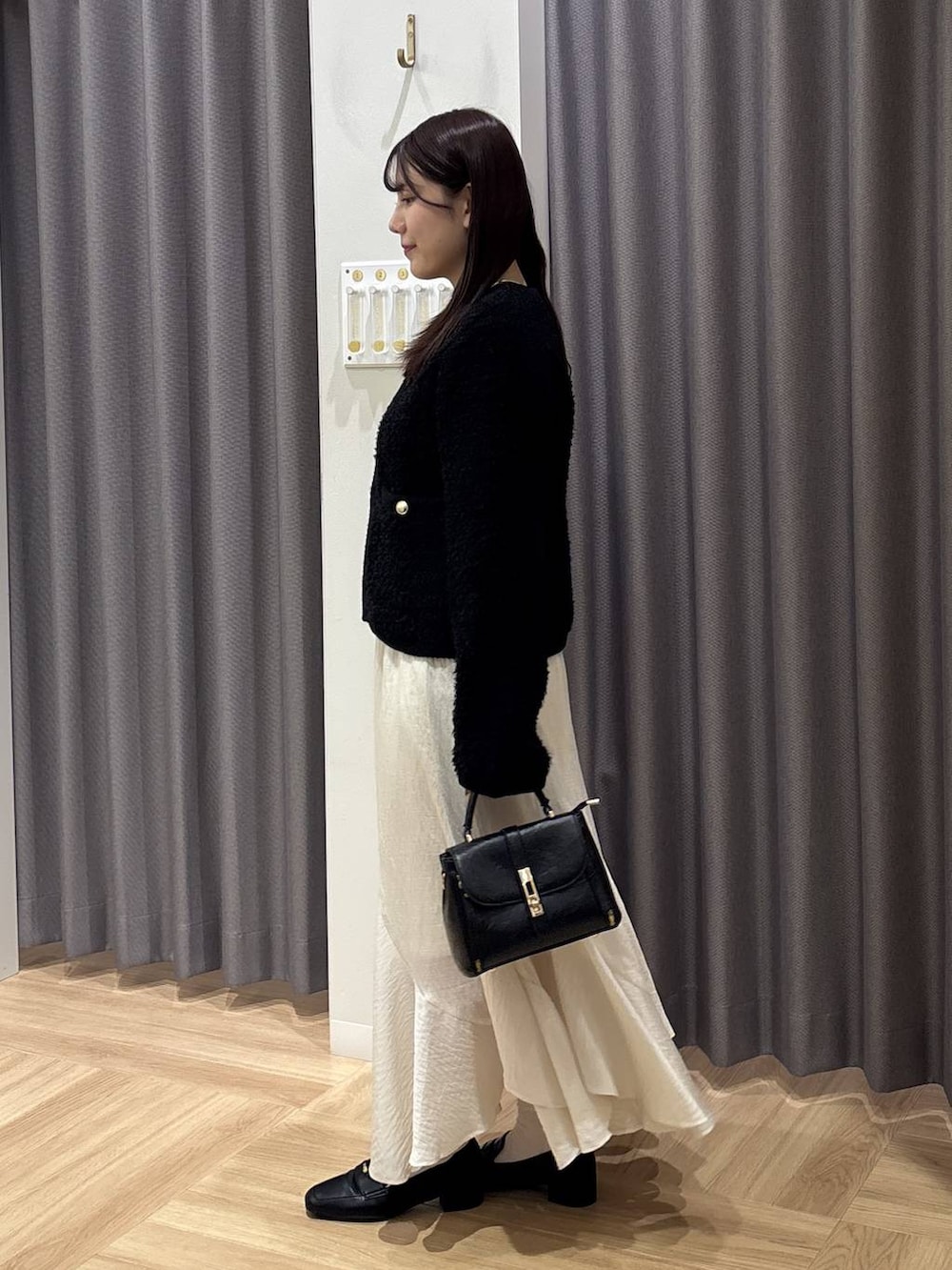 ホワイト系のスカート、ブラック系のカーディガン/ボレロ、ブラック系のローファーを着用したレディースの秋コーディネートの2枚目の写真
