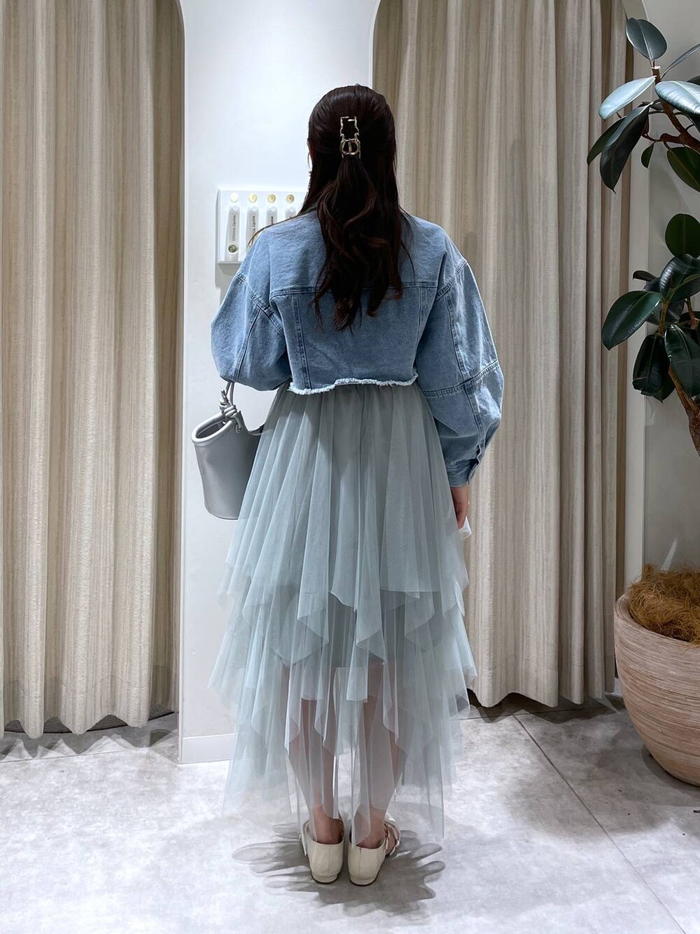 シルバー系のハンドバッグ、グリーン系のスカート、ホワイト系のパンプスを着用したレディースの春コーディネートの3枚目の写真