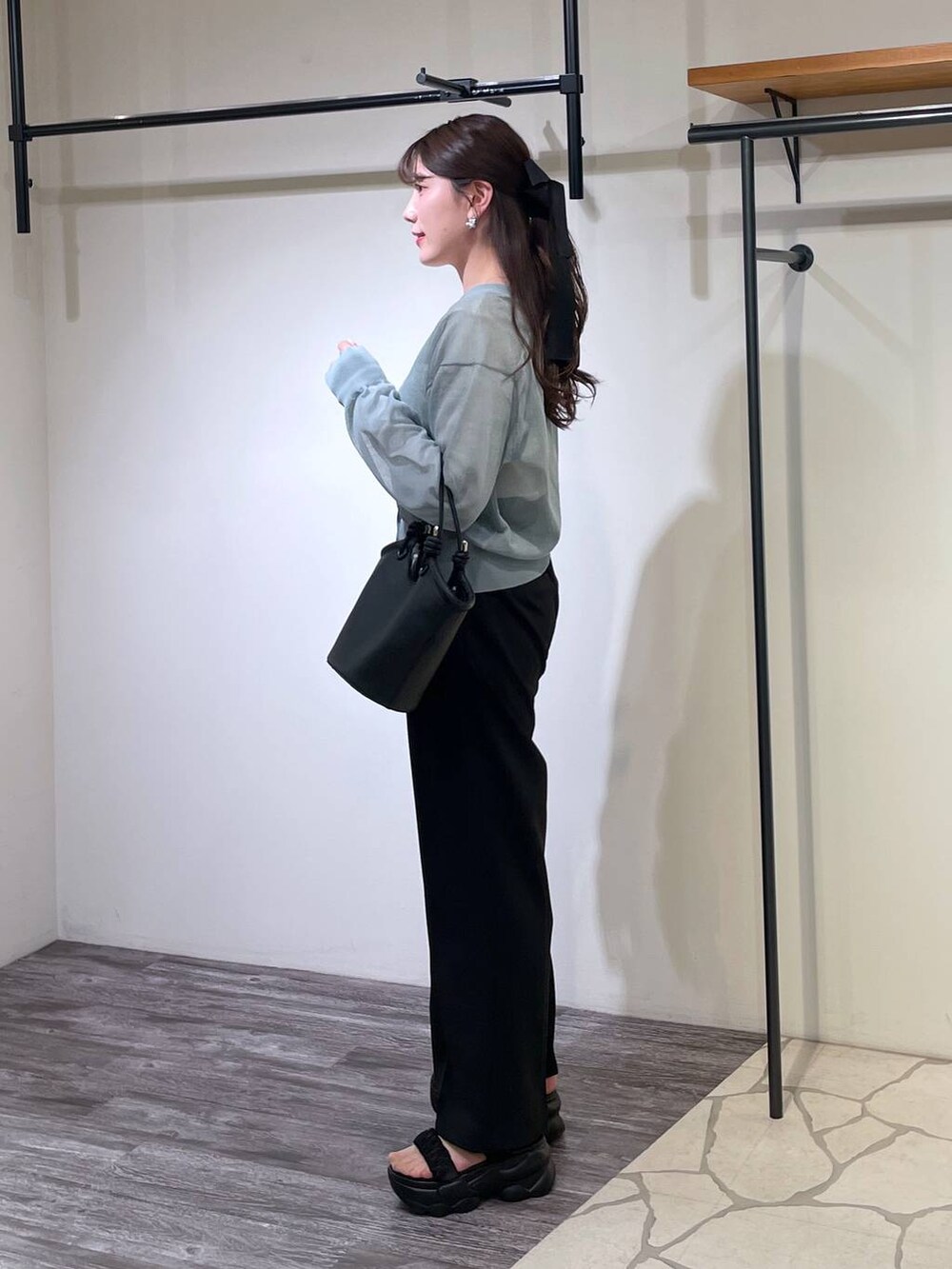 ブラック系のハンドバッグ、ブラック系のスラックス、ホワイト系のTシャツ/カットソーを着用したレディースの春コーディネートの2枚目の写真